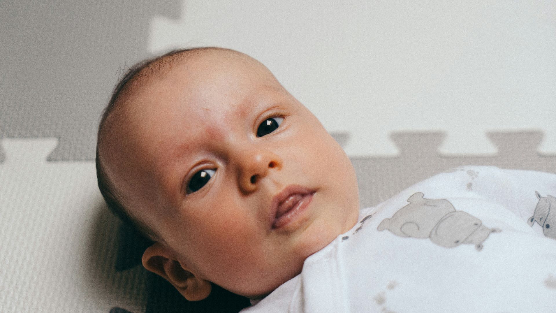 a close up of a baby laying on a mat