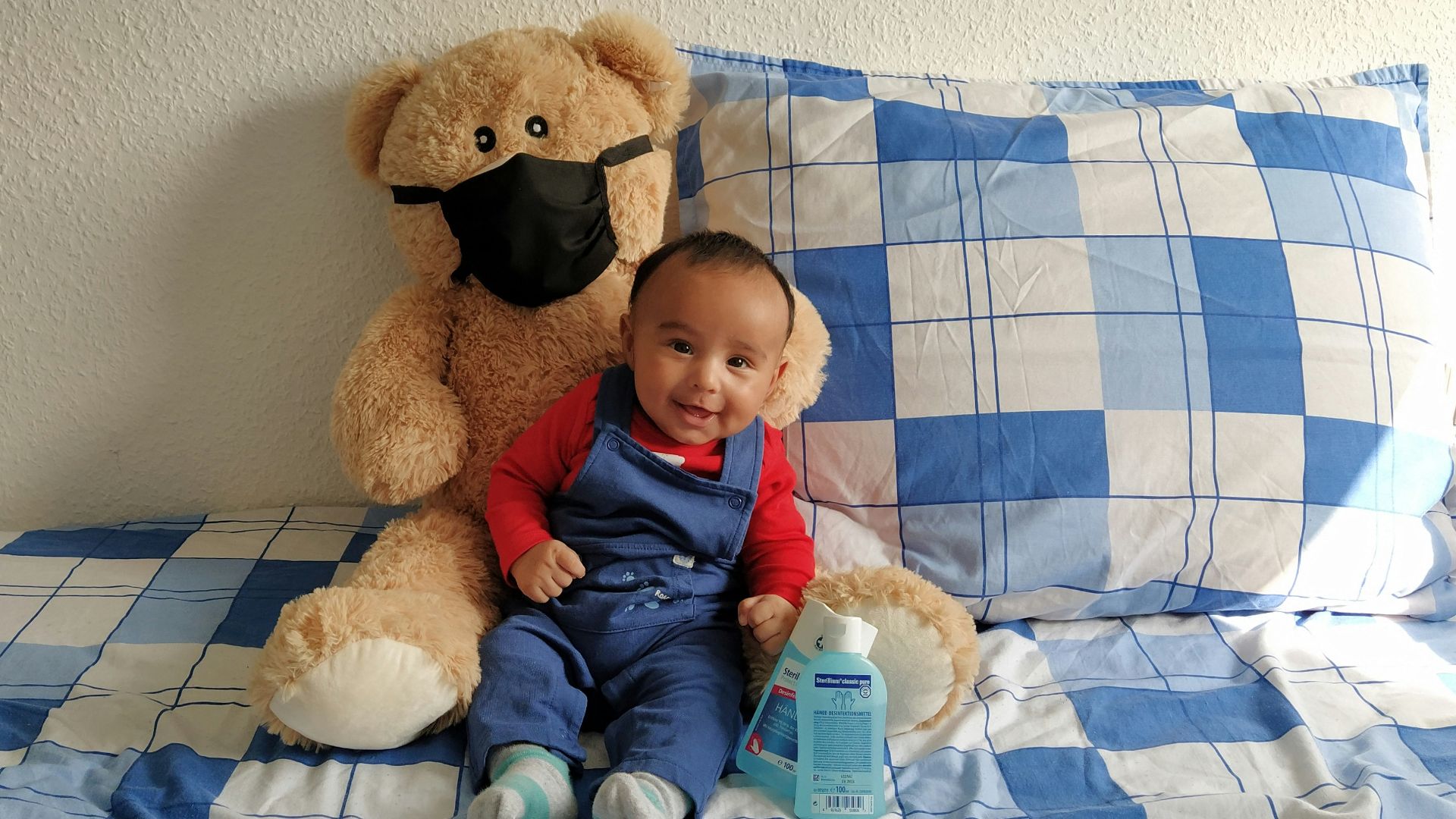a baby sitting on a bed next to a teddy bear