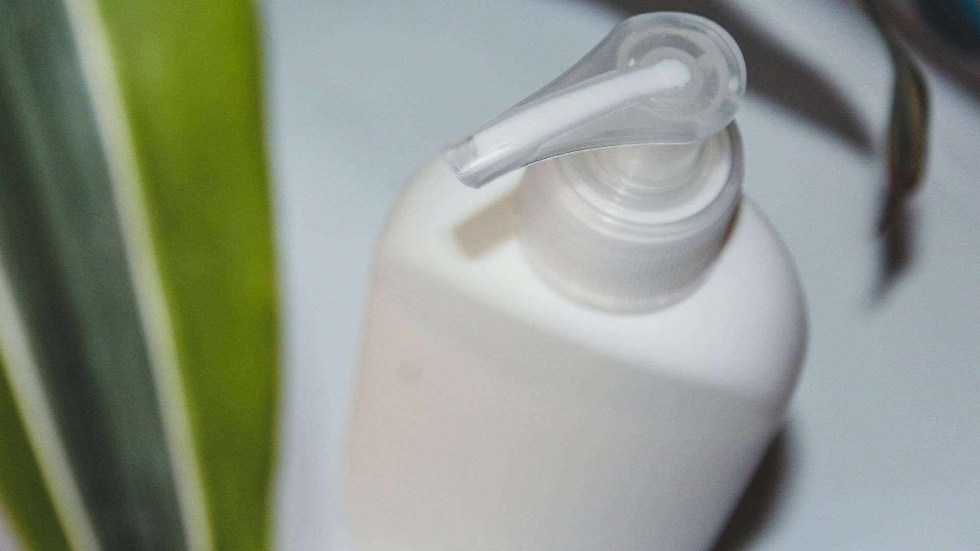 a bottle of lotion sitting next to a plant