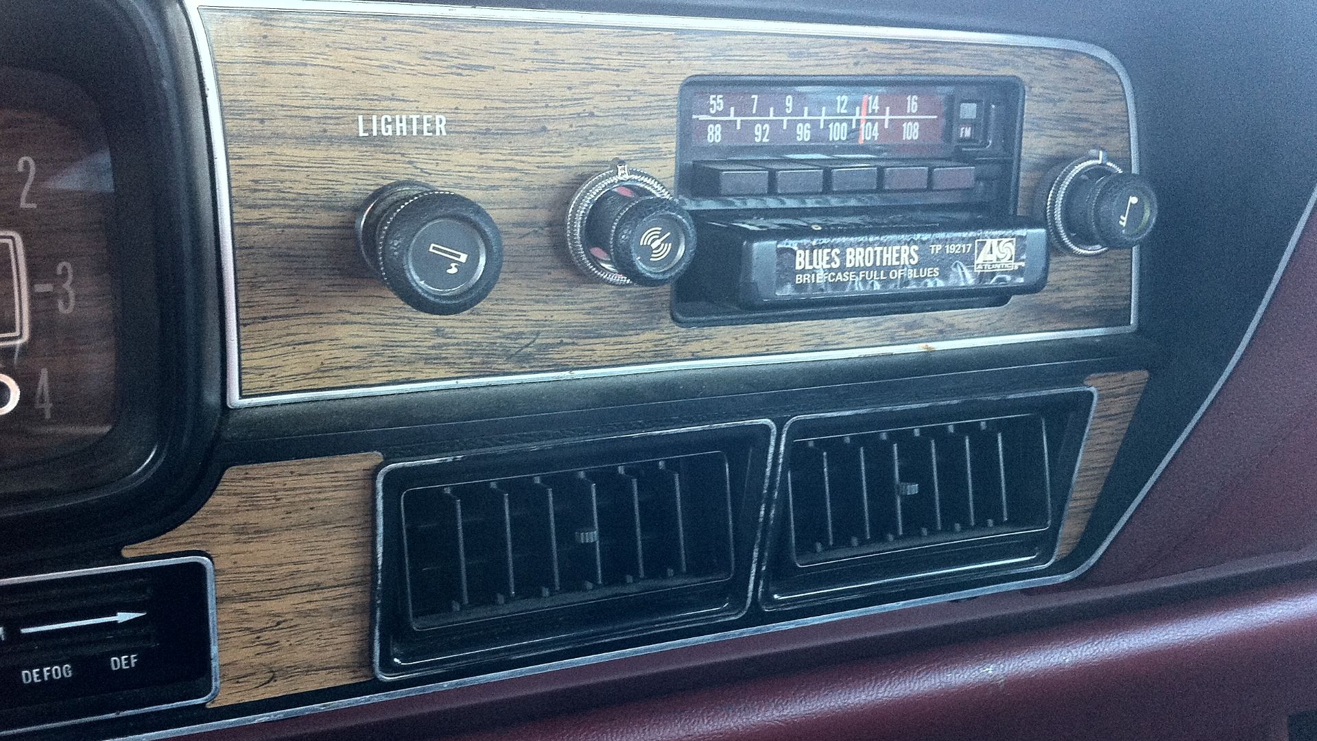 Detail of the factory installed AM/FM/8-track stereo audio unit in the instrument panel of a 1978 AMC Matador four-door sedan (made by American Motors Corporation). Also shown is the a tape cartridge in