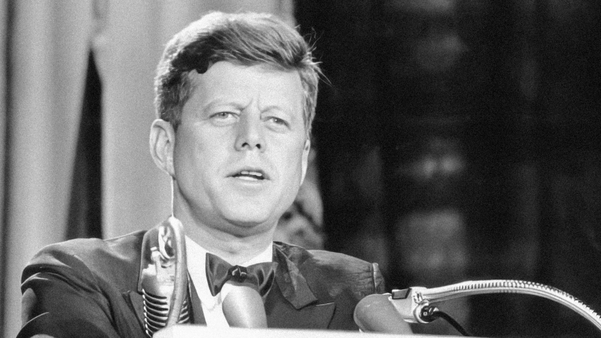 a man in a suit and tie standing at a podium
