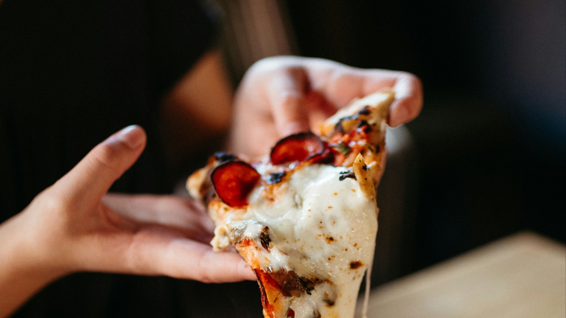 a person takes a slice of pizza