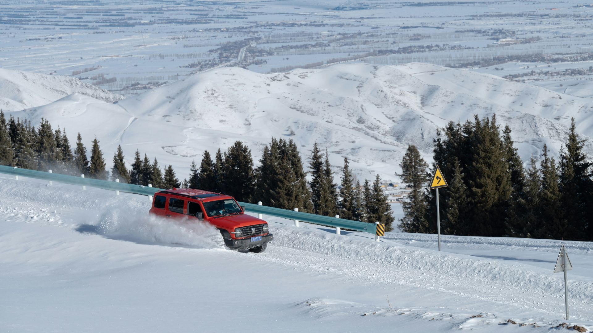 a red truck driving down a snow covered slope
