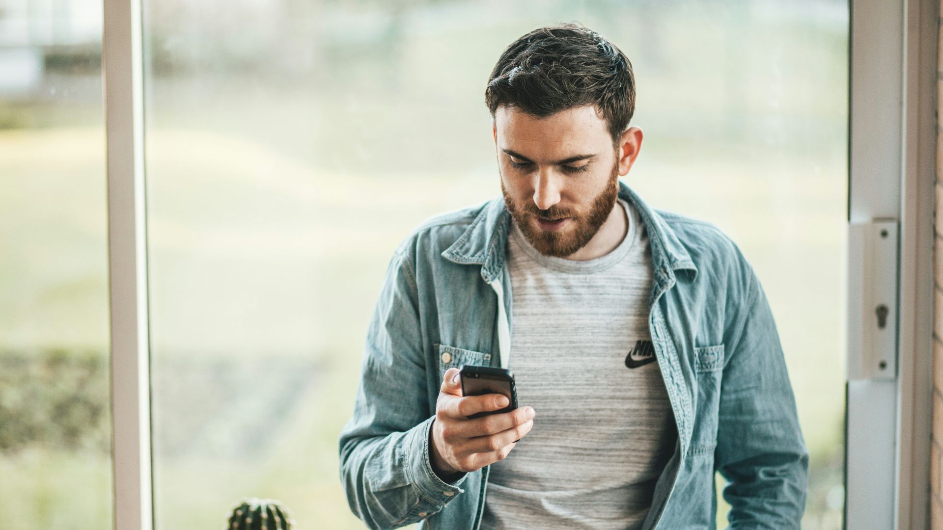 man holding a smartphone near the window
