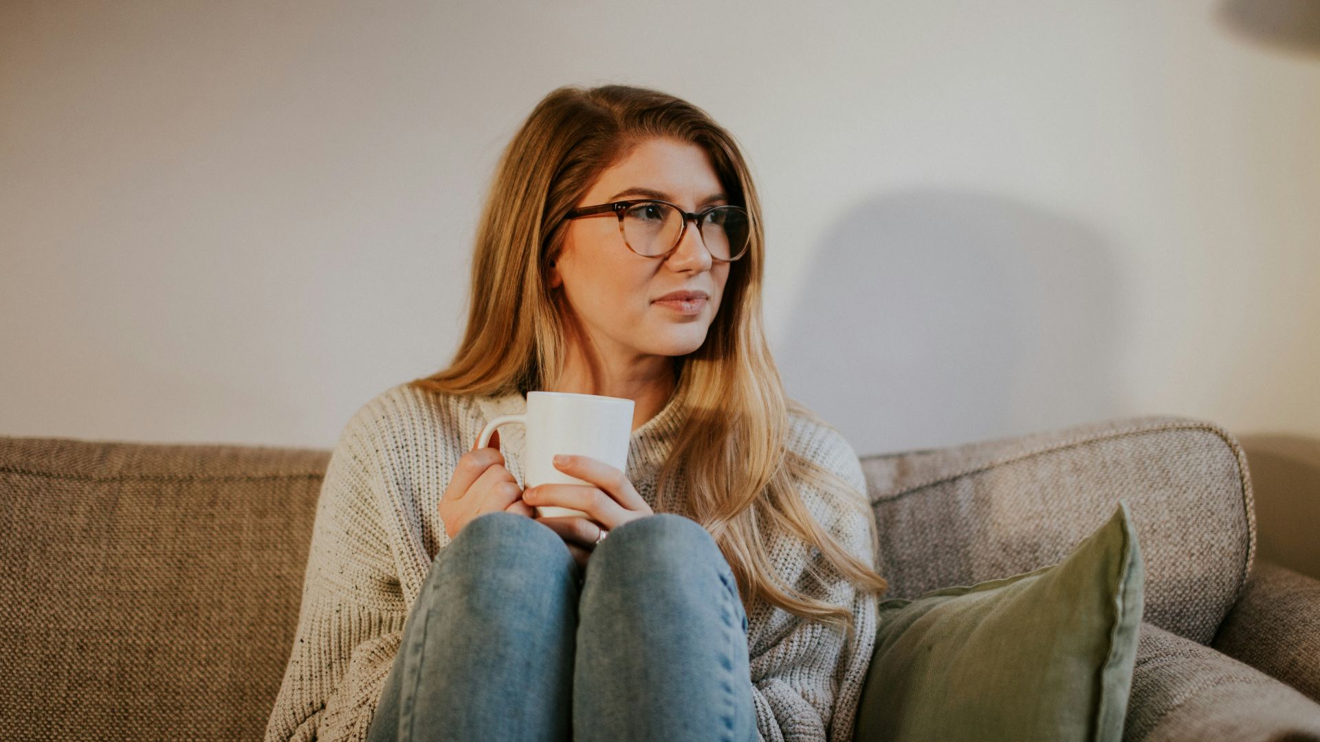 woman in blue denim jeans sitting on gray sofa