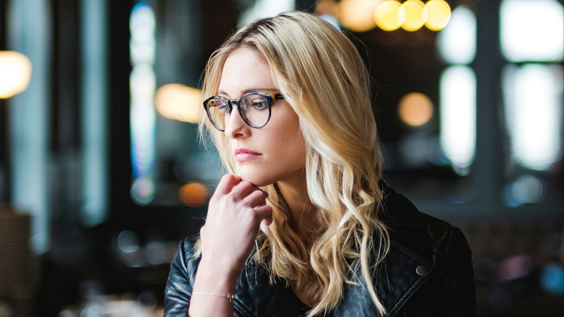 woman resting her head on her hands while looking sideways inside well lit room