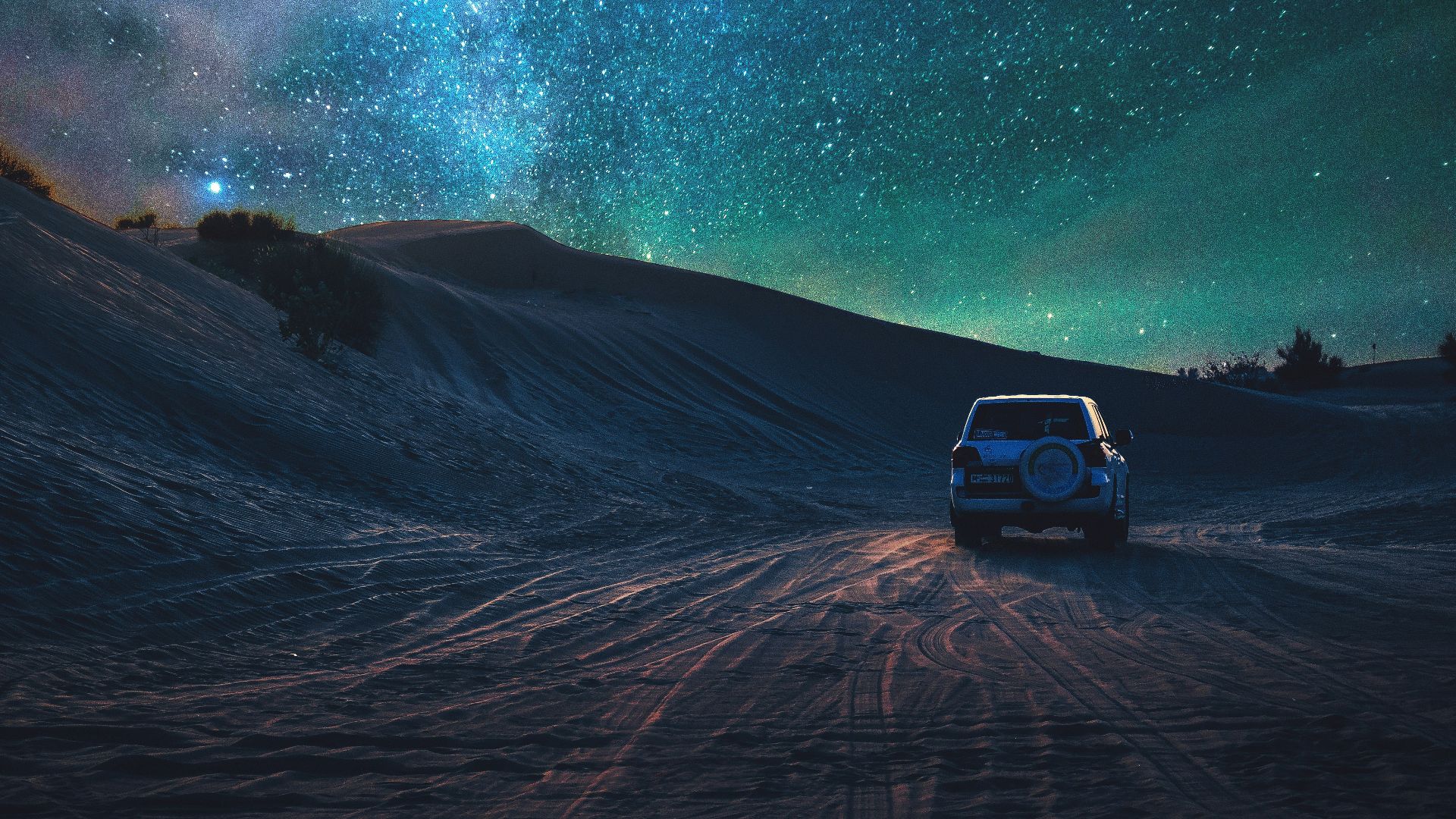 gray vehicle traveling on desert during nighttime