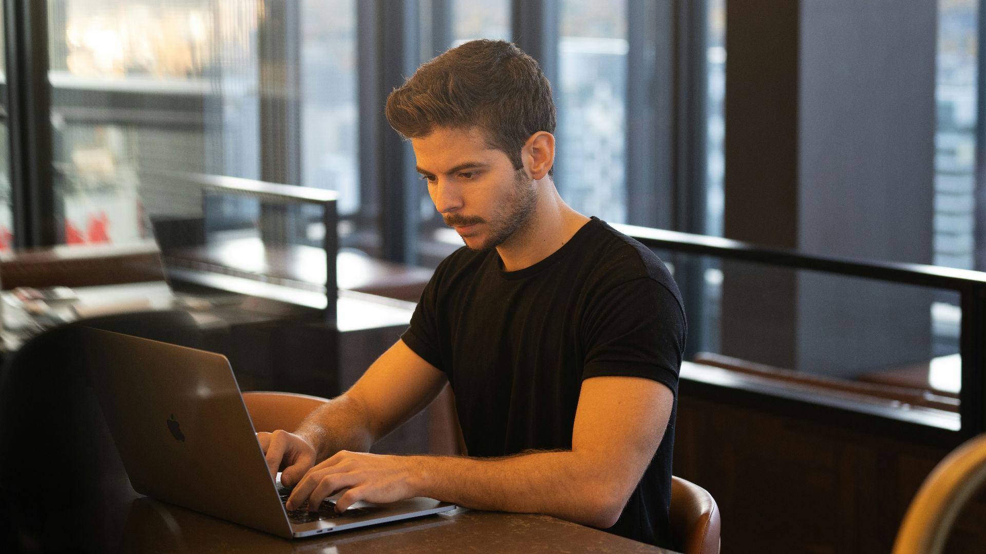 man in black crew neck t-shirt using macbook