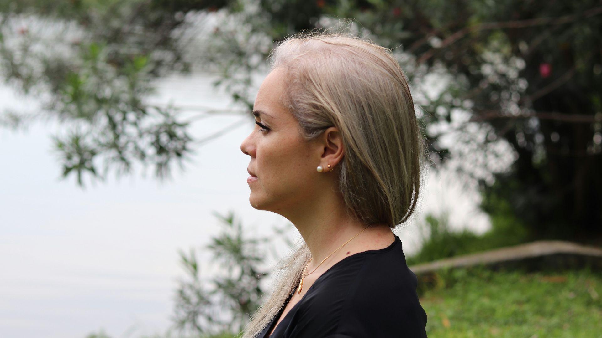 a woman with blonde hair standing in front of a body of water