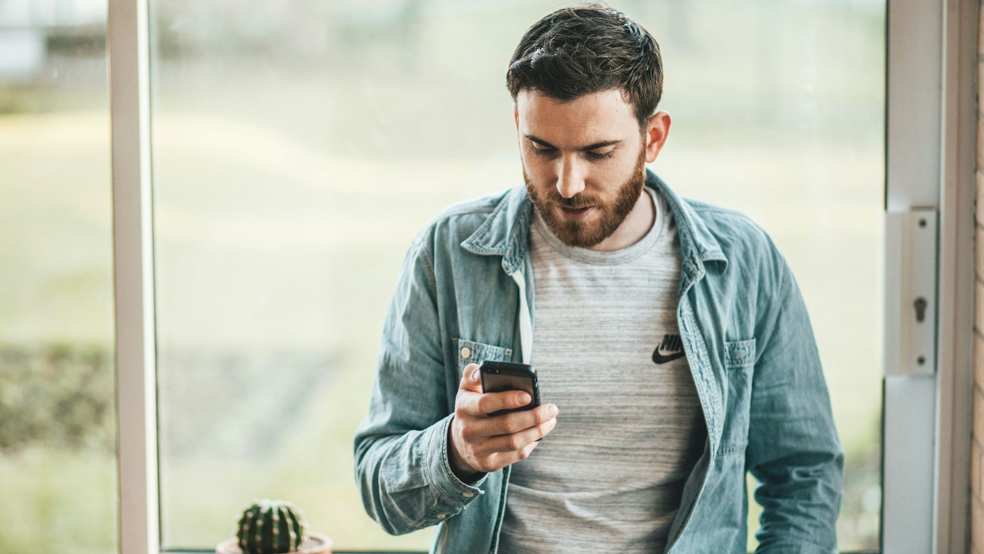 man holding a smartphone near the window