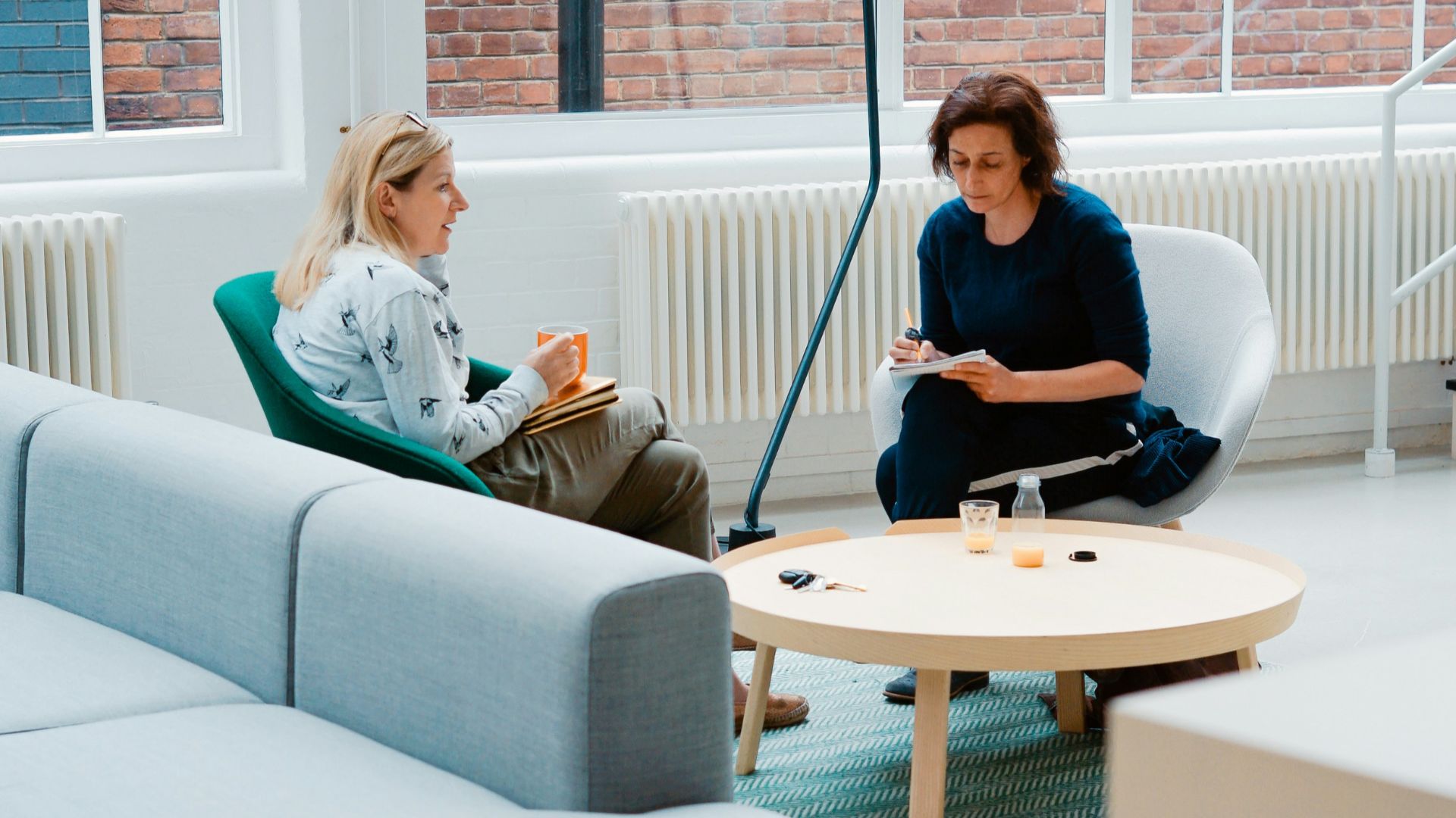 two woman sits on sofa chairs inside house