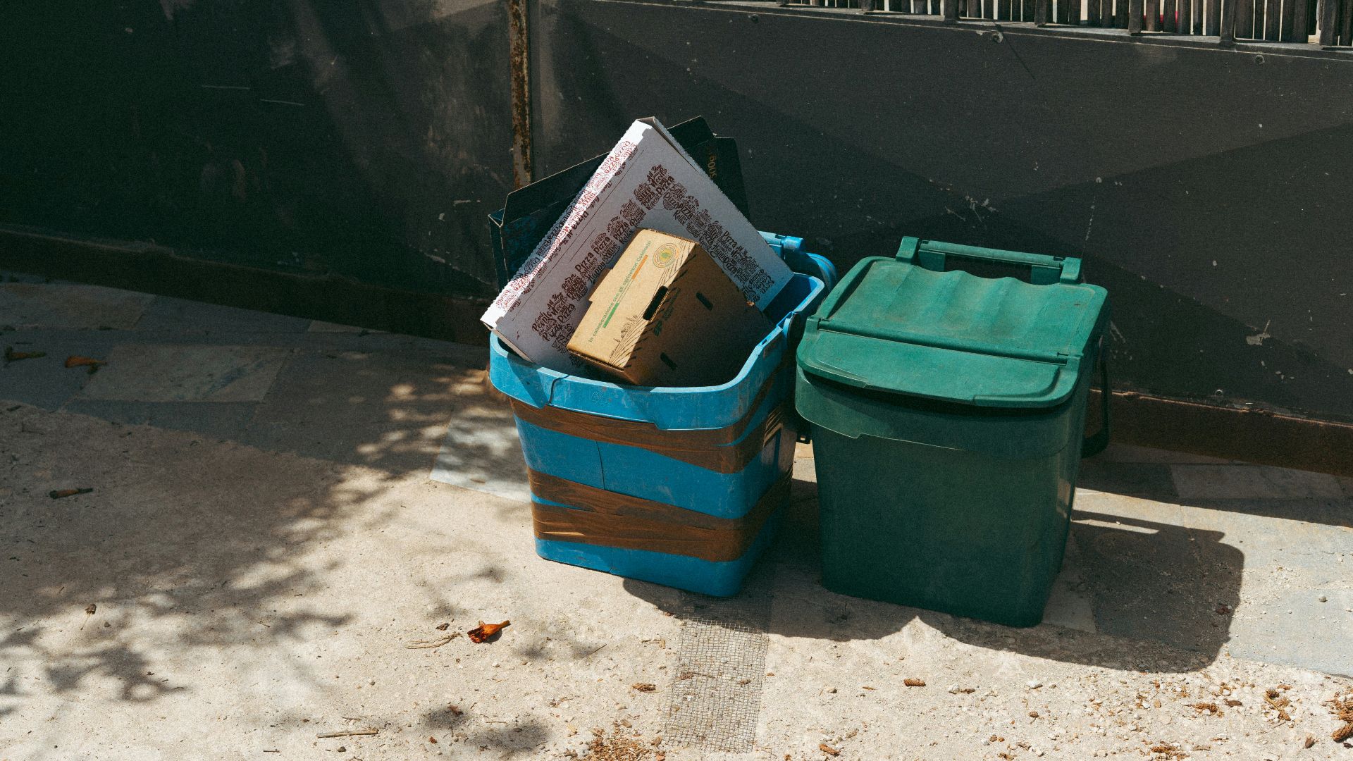 Two bins, one blue and one green, filled with trash.
