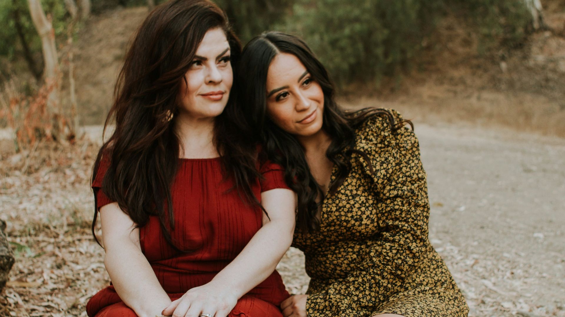 2 women sitting on brown wooden bench