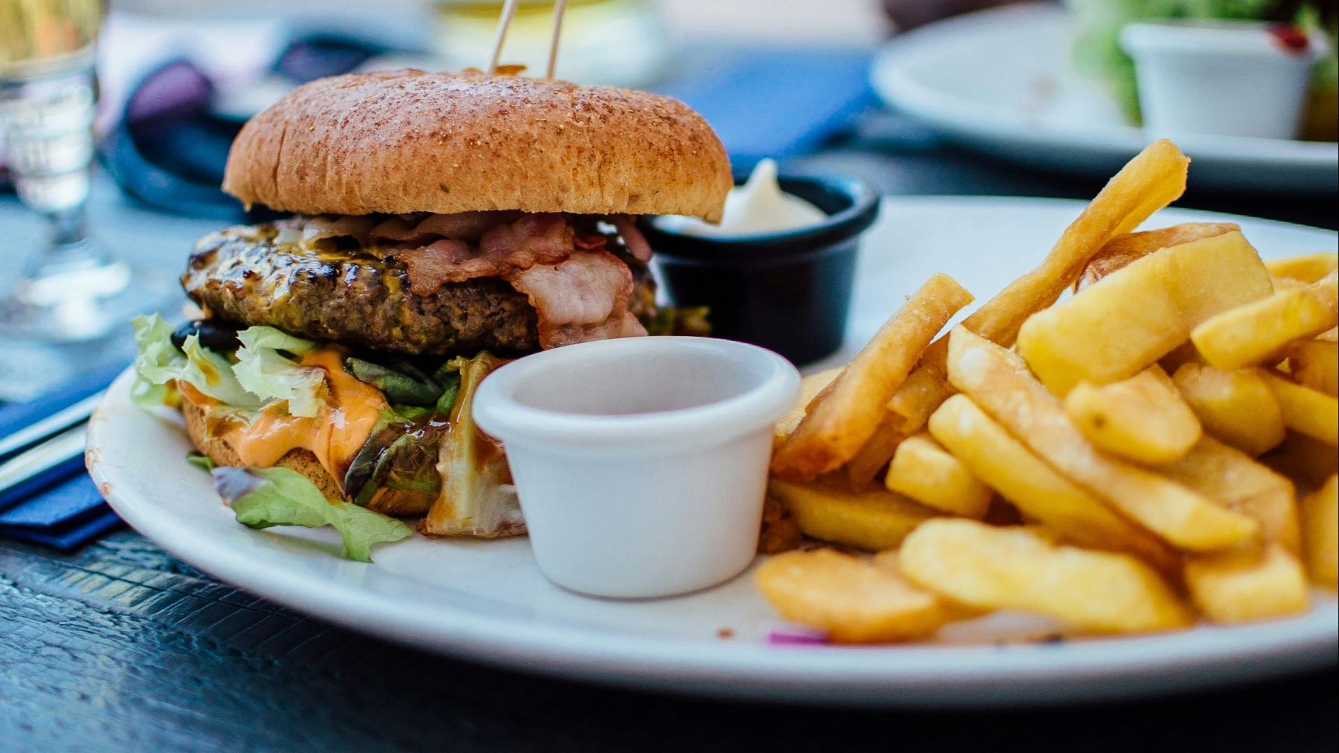 selective focus photography of burger patty, mayonnaise, and French fries served on platter
