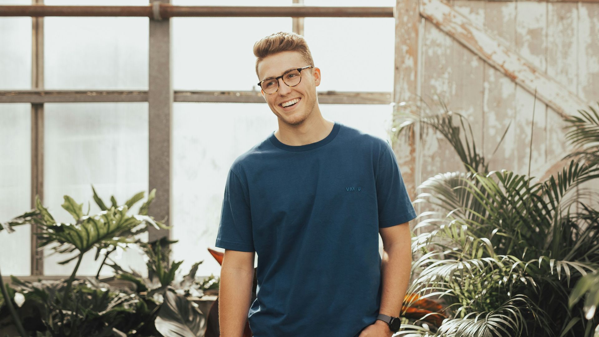 man in blue crew-neck top standing near plants