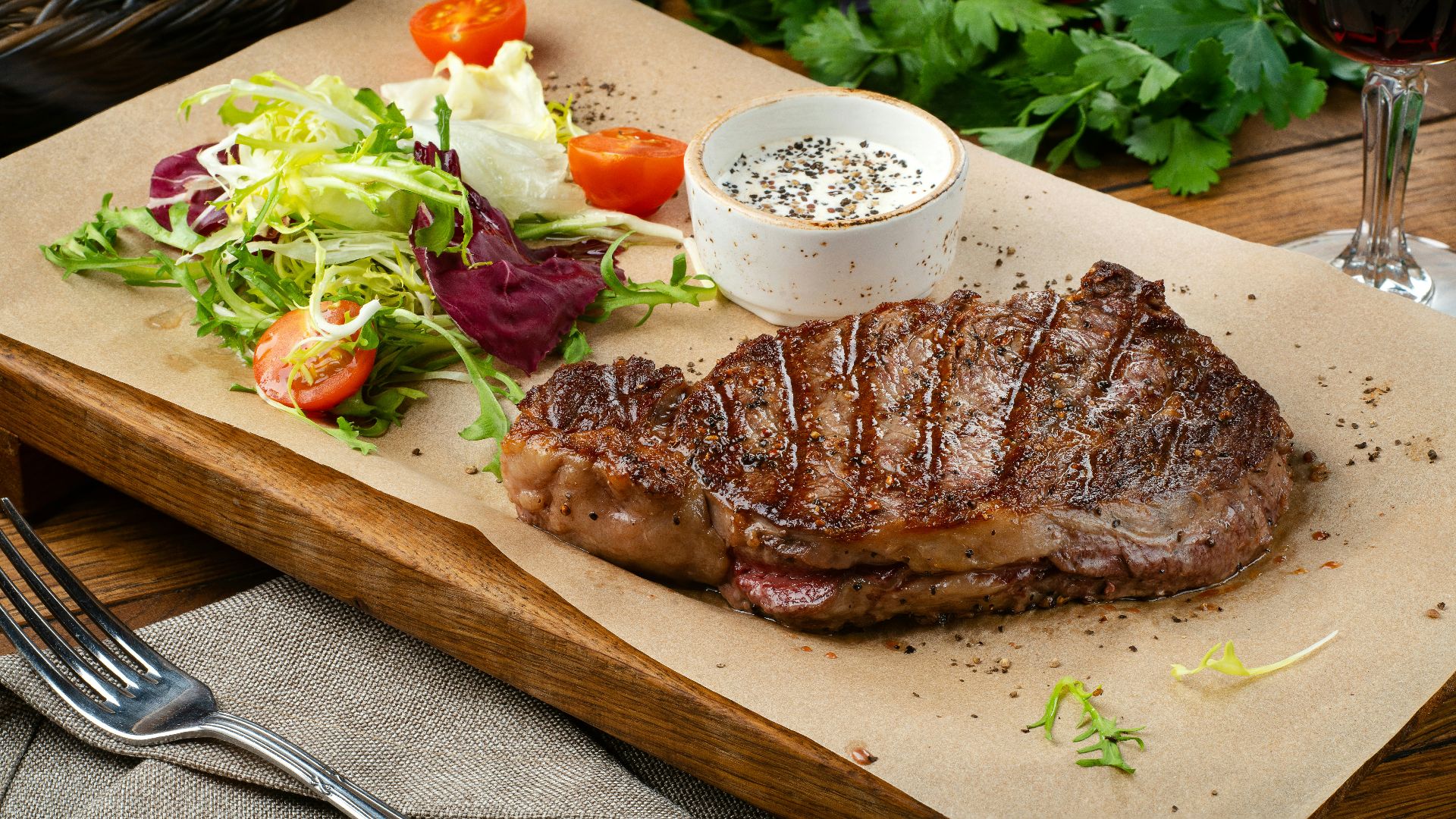 a steak with a side of salad and a glass of wine