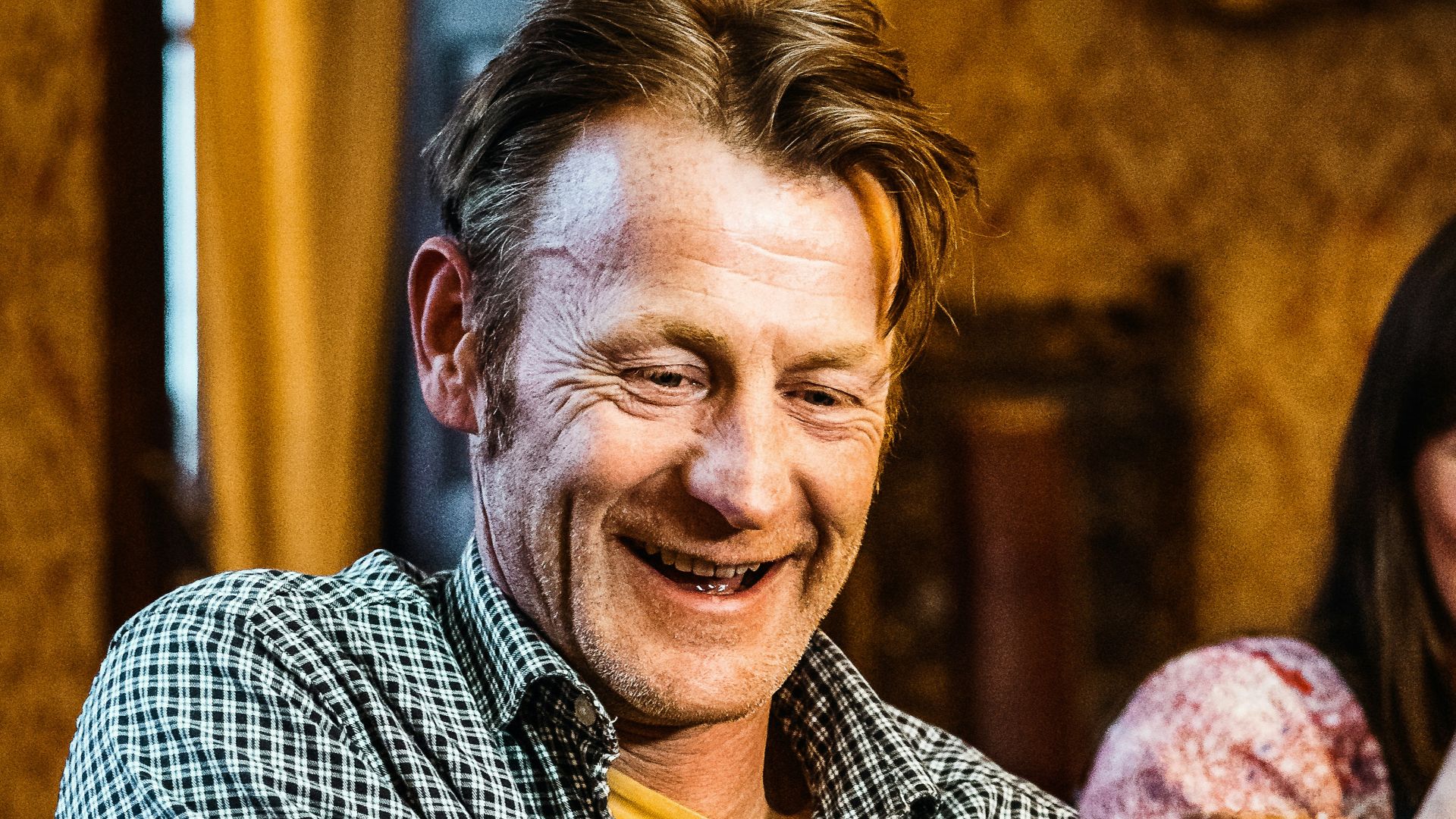man in blue and white checkered button up shirt holding bread