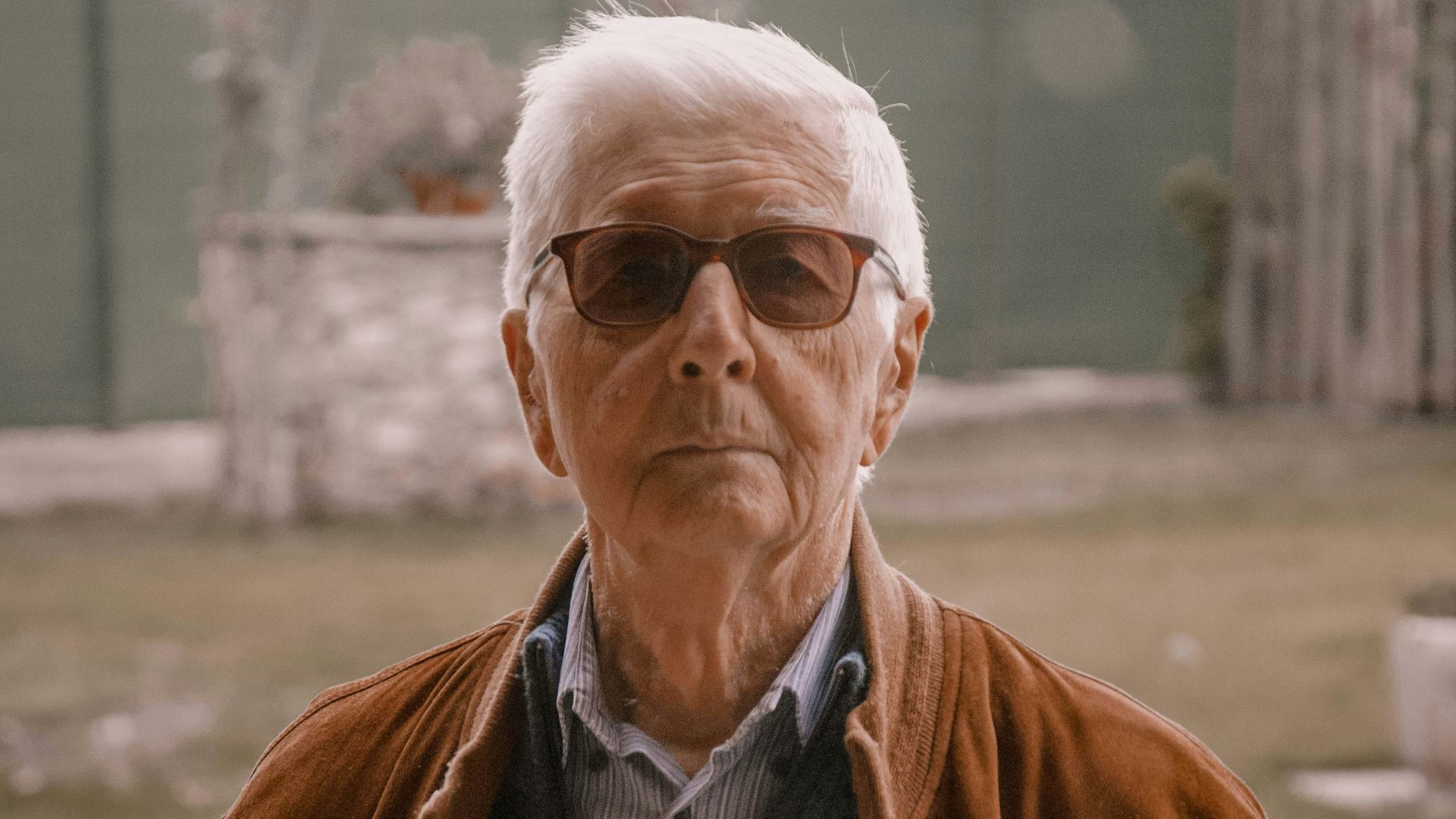 man in brown jacket wearing black framed eyeglasses