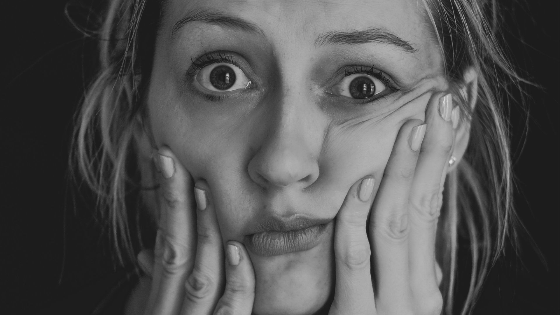 grayscale photo of woman covering her face with her hand