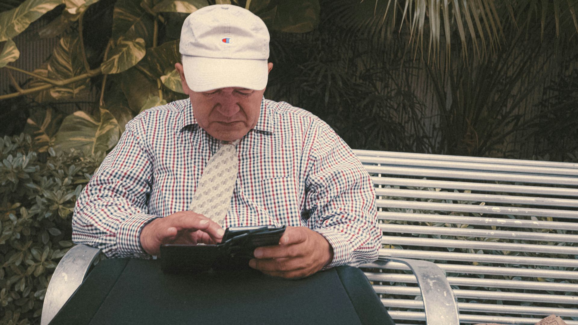 a man sitting on a bench looking at his cell phone