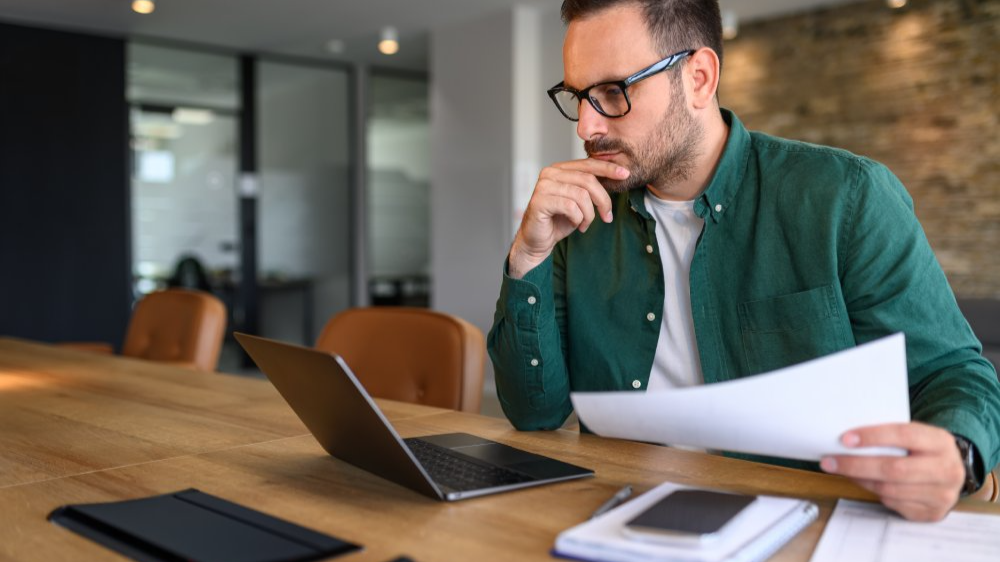 Focused young businessman auditing revenue report and planning budget