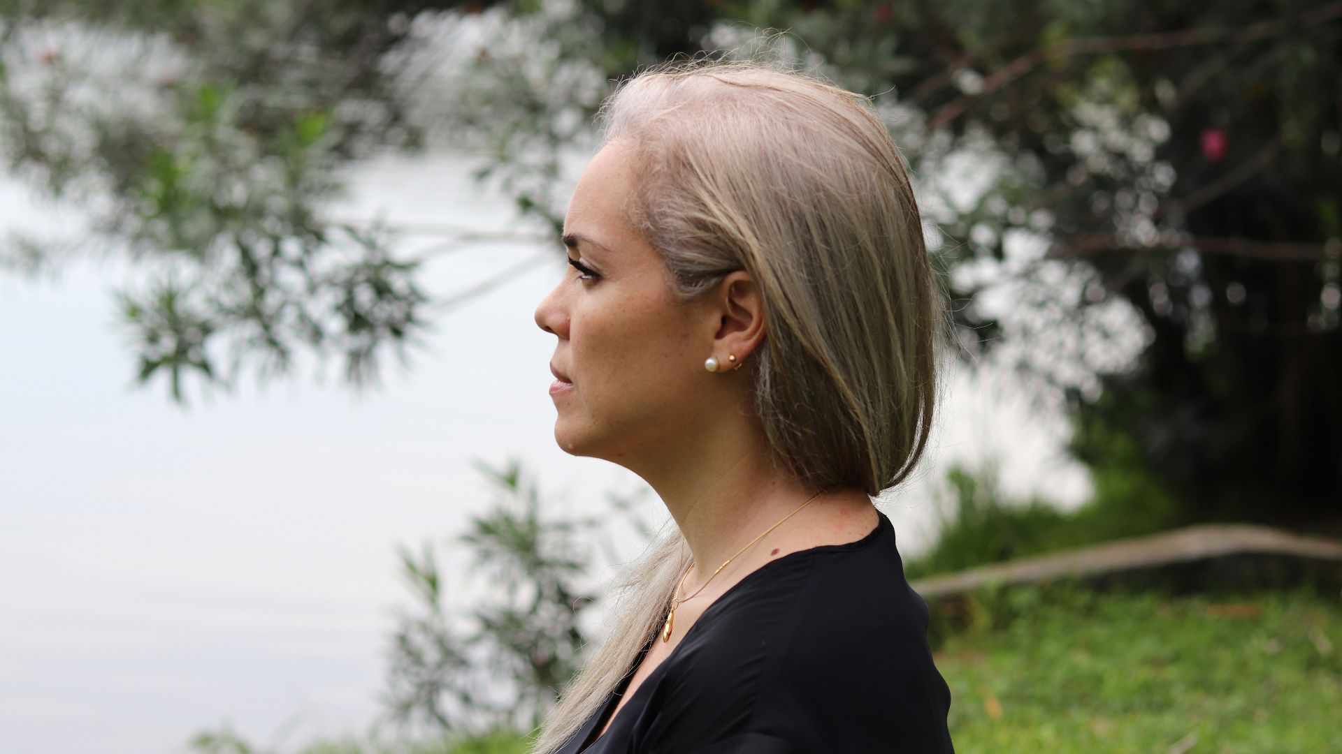a woman with blonde hair standing in front of a body of water