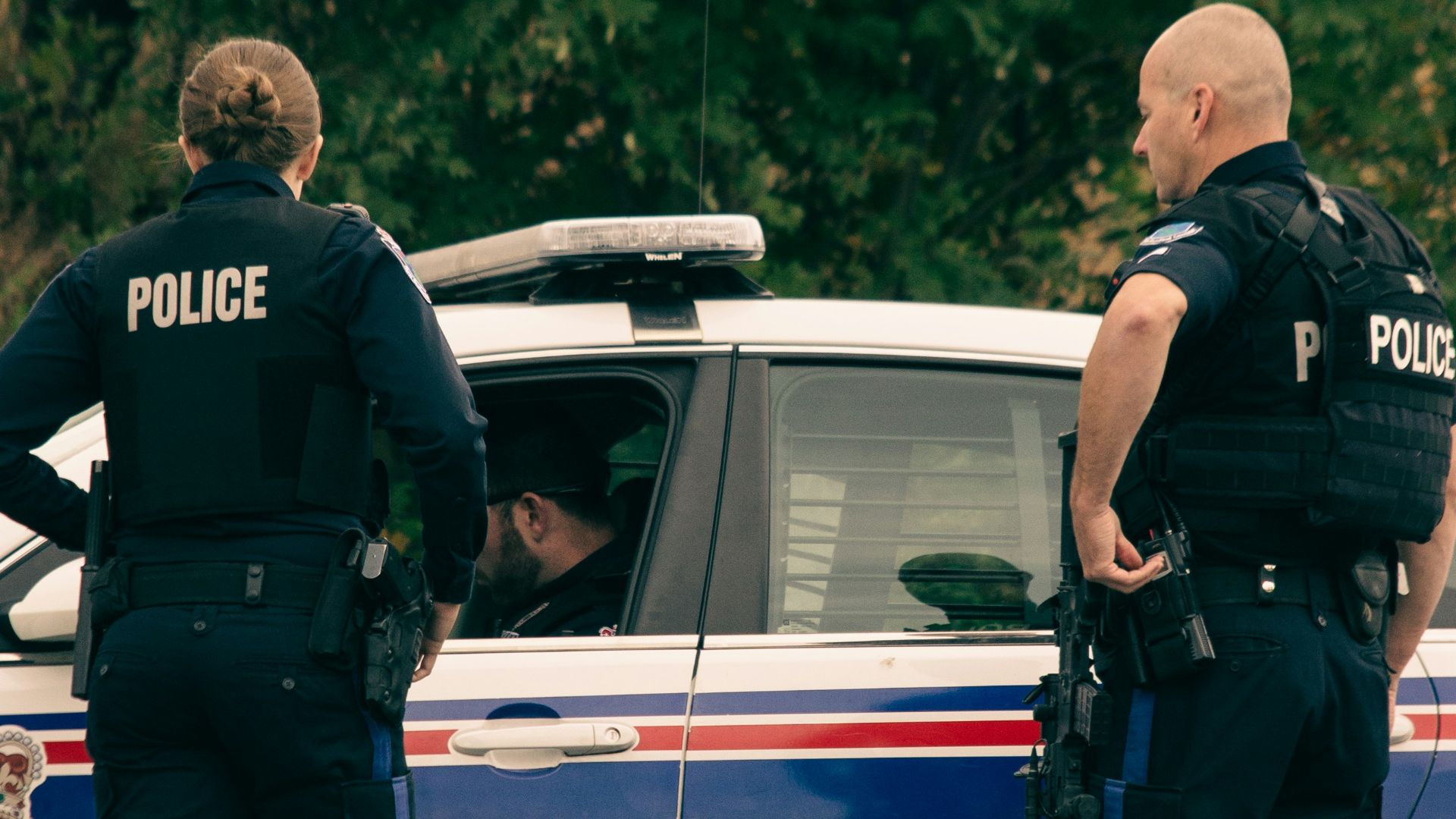 2 police men standing on white police car during daytime