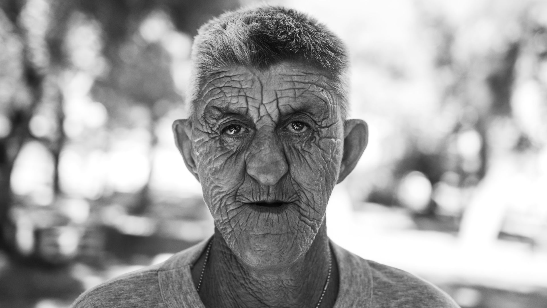 Elderly man with weathered face looks forward.