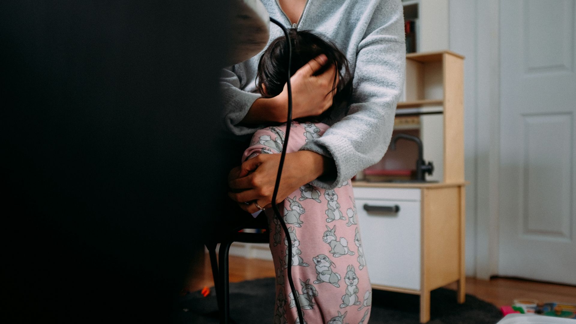 woman in gray cardigan and pink floral dress holding black coated wire