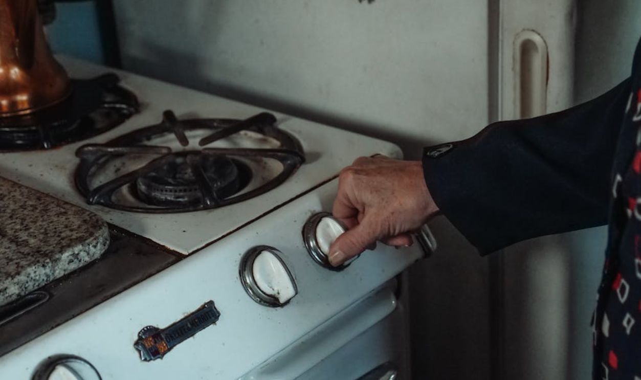 A Person Holding a Knob on a Gas Stove