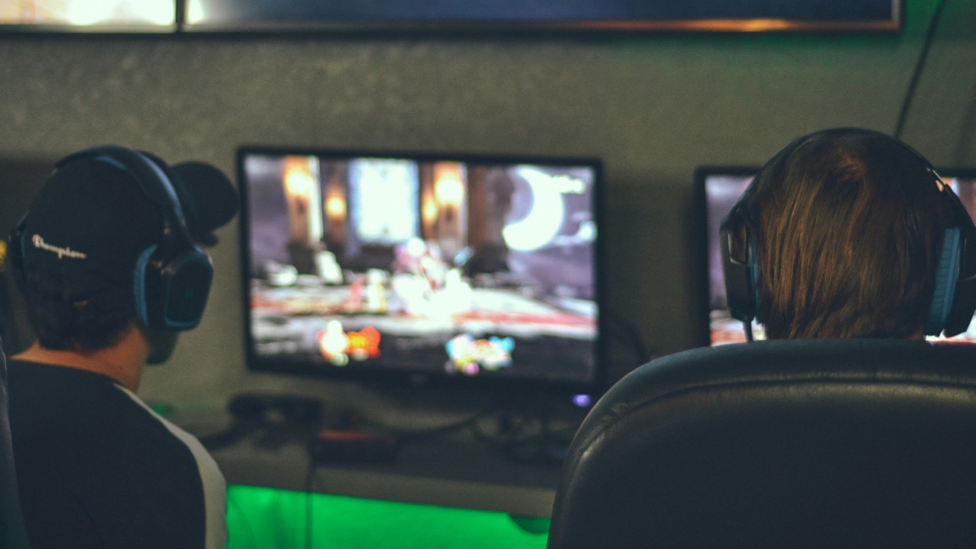 selective focus photography of two persons playing game in front of monitors