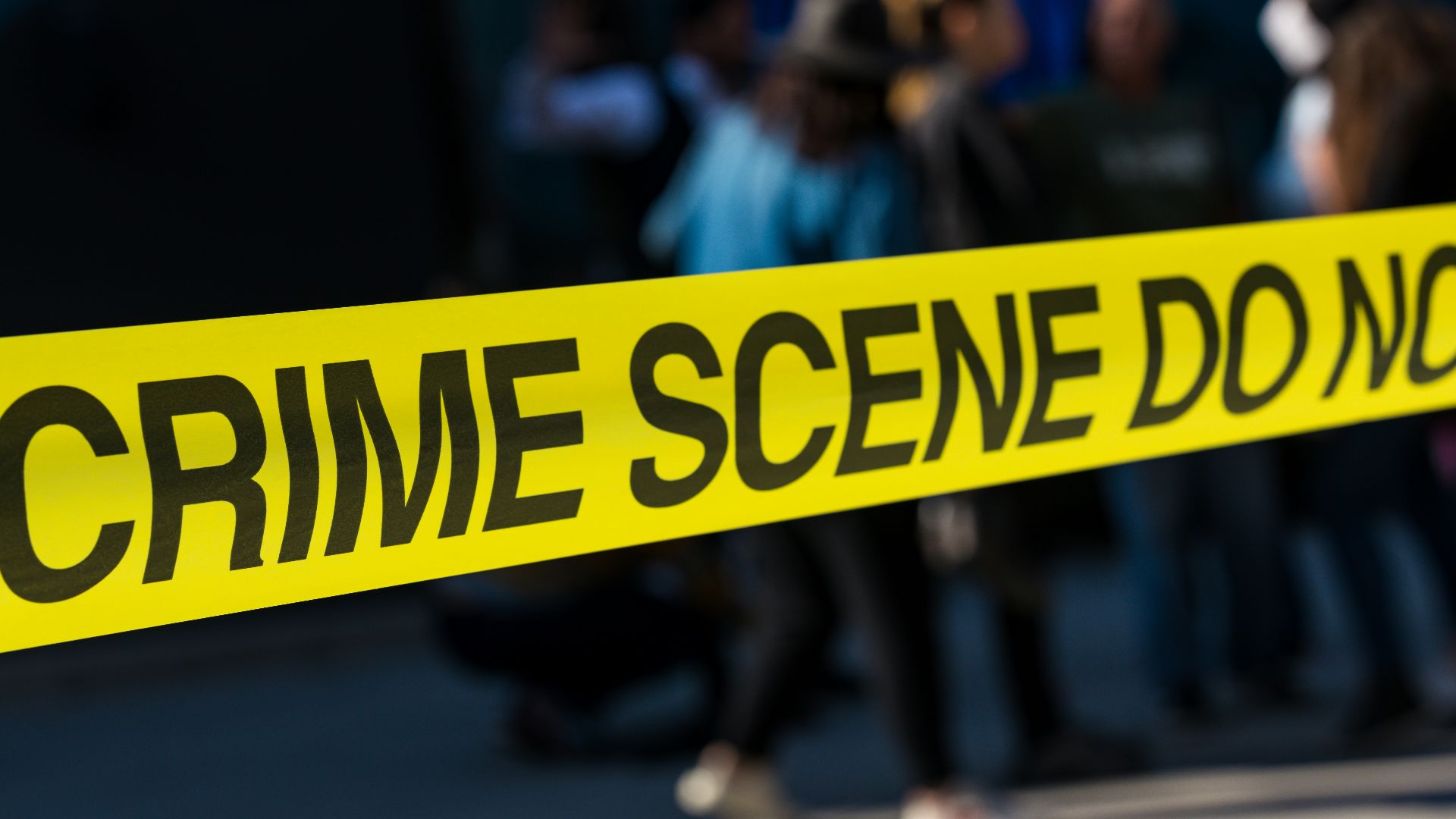 a group of people standing next to a yellow police line