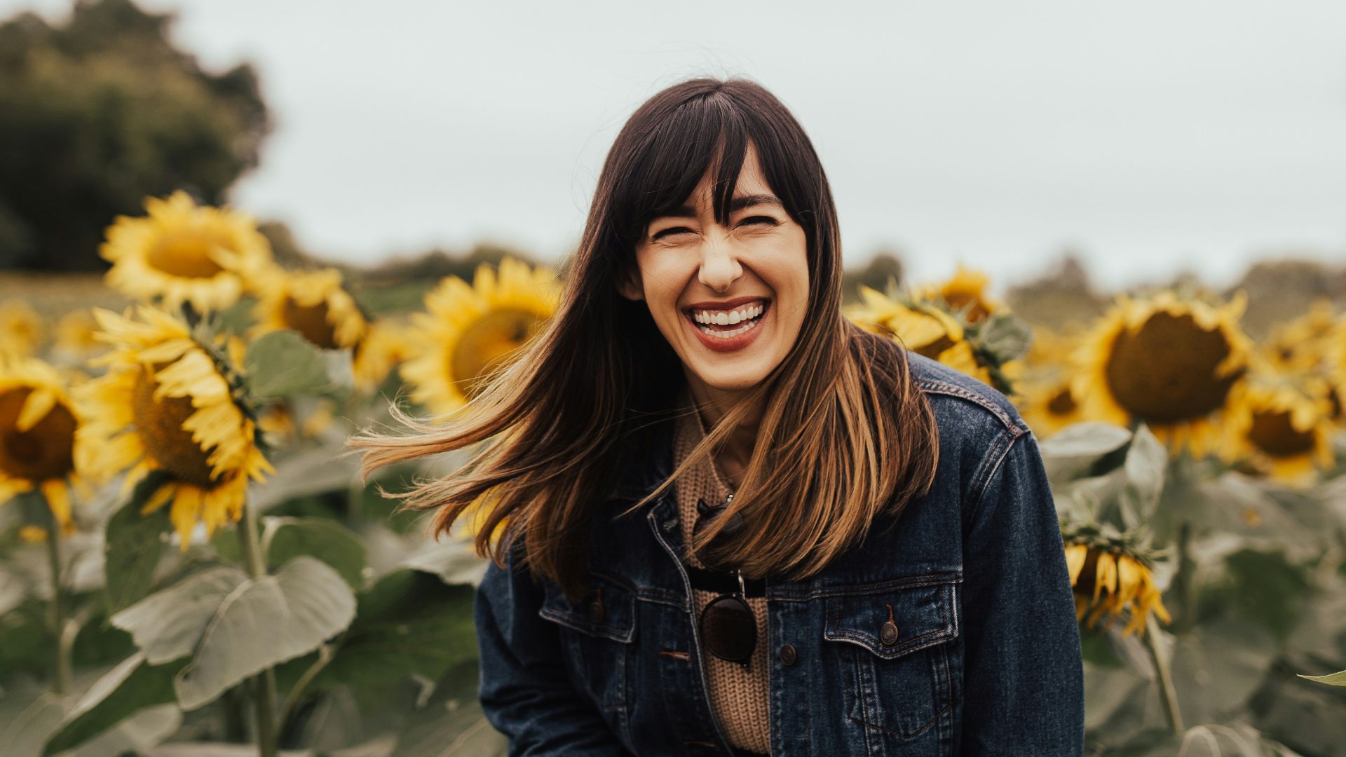 smiling woman standing beside sunflowers