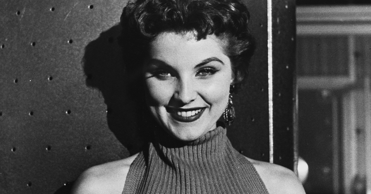 a black and white photograph of Debra Paget, American Actress, smiling at the camera