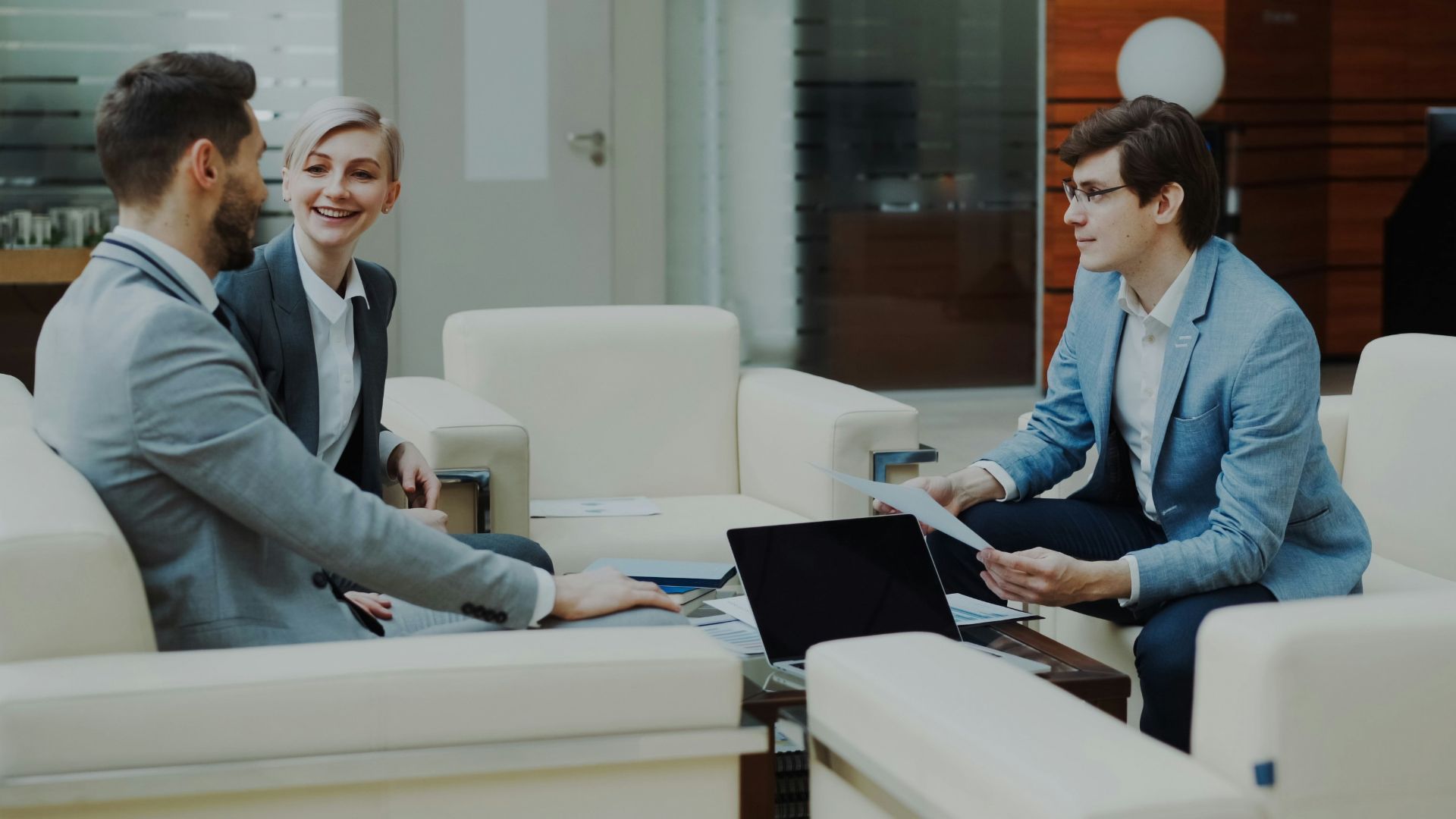 Three professionals in a modern office lounge.