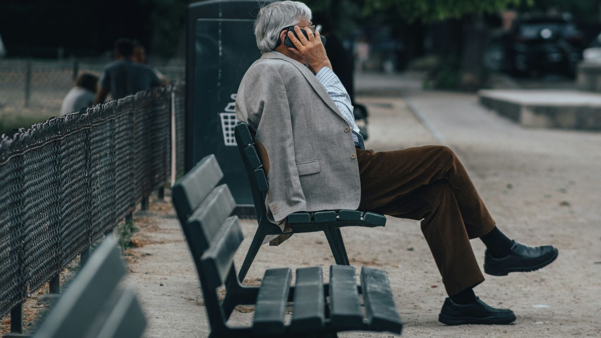 man in brown jacket sitting on bench