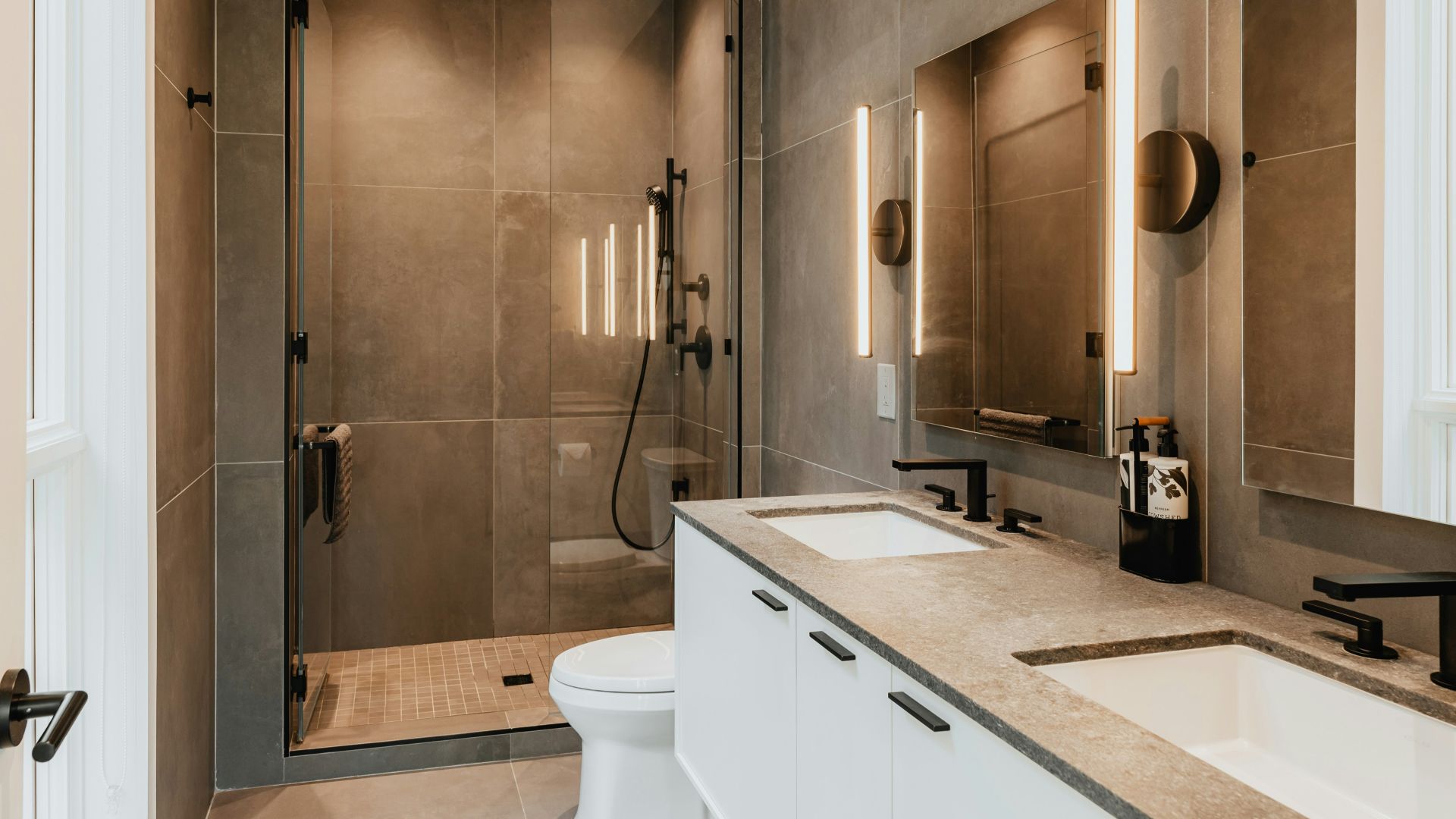 a bathroom with two sinks, a toilet and a shower