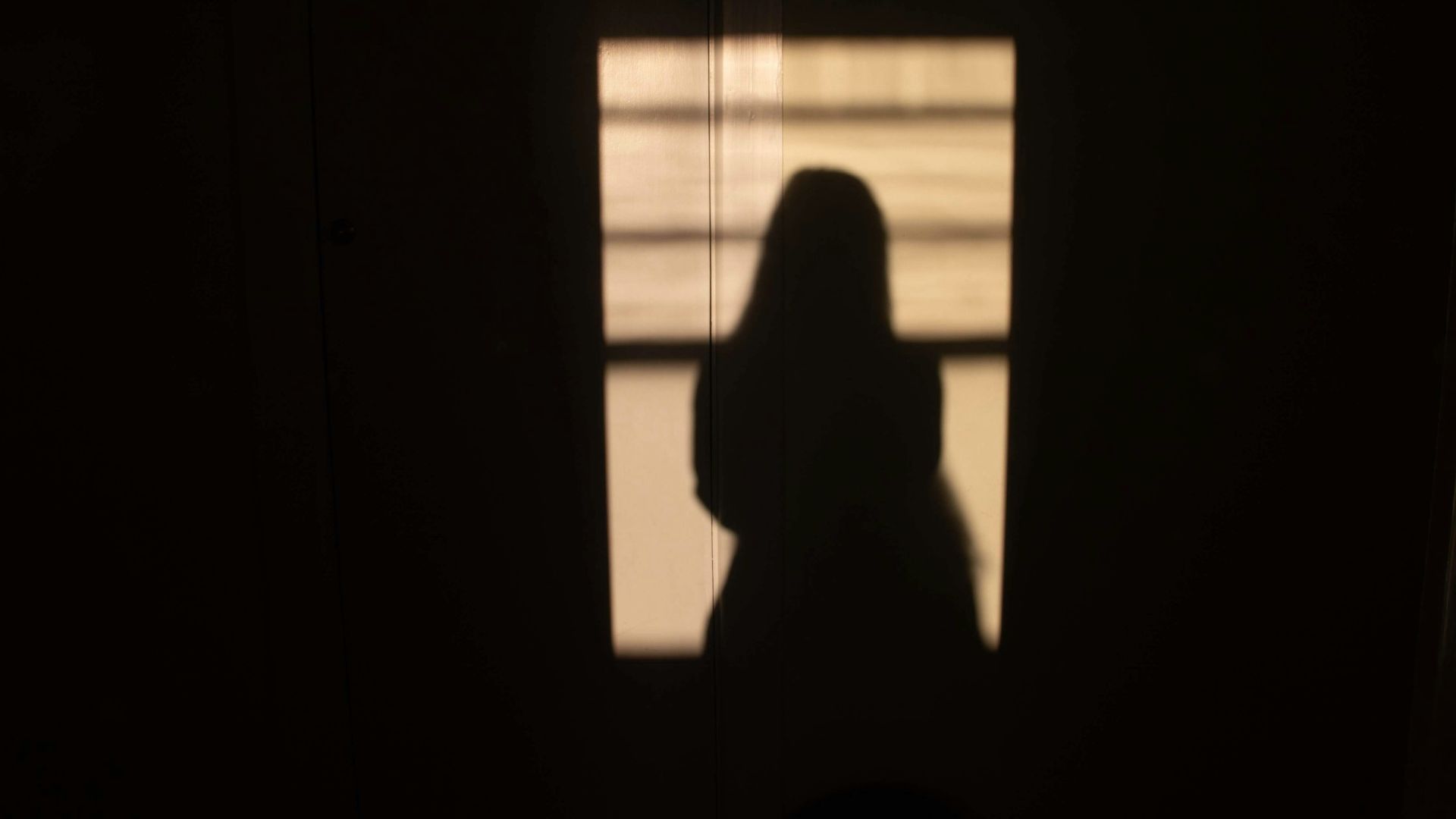 silhouette of person sitting on window