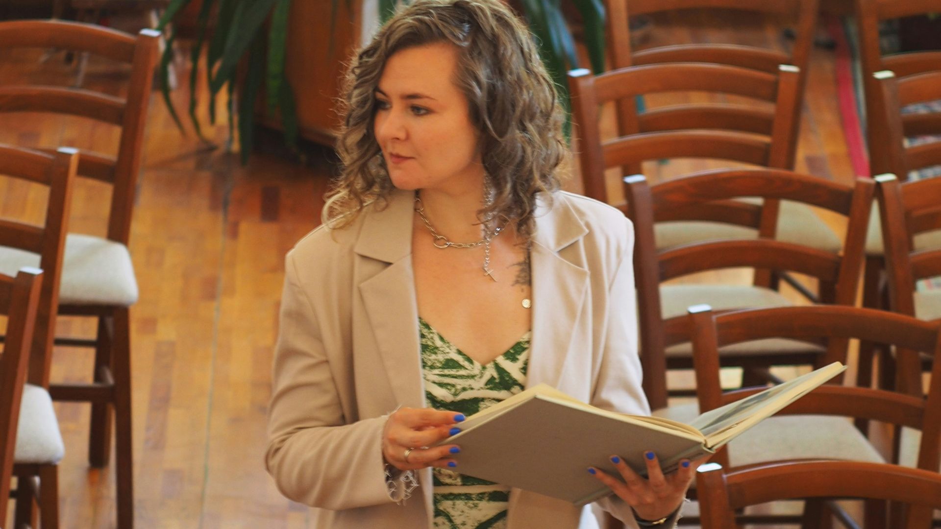 A woman standing in a room filled with wooden chairs