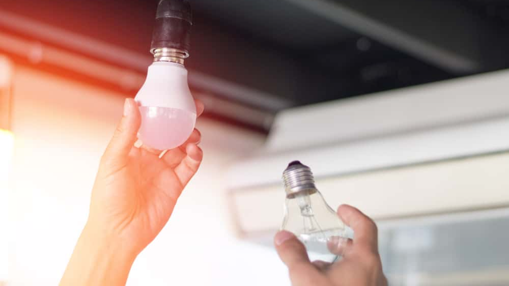 man changing compact-fluorescent (CFL) bulbs with new LED light bulb.