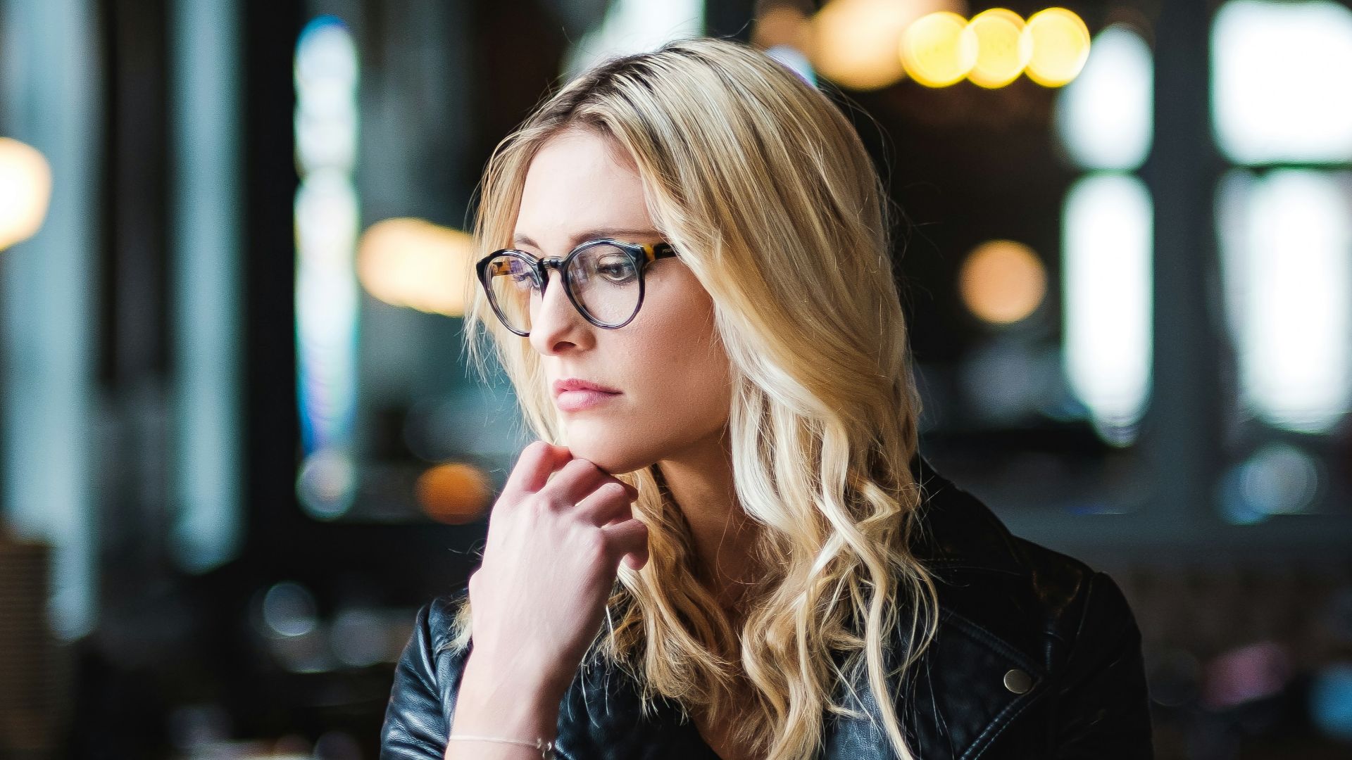 woman resting her head on her hands while looking sideways inside well lit room
