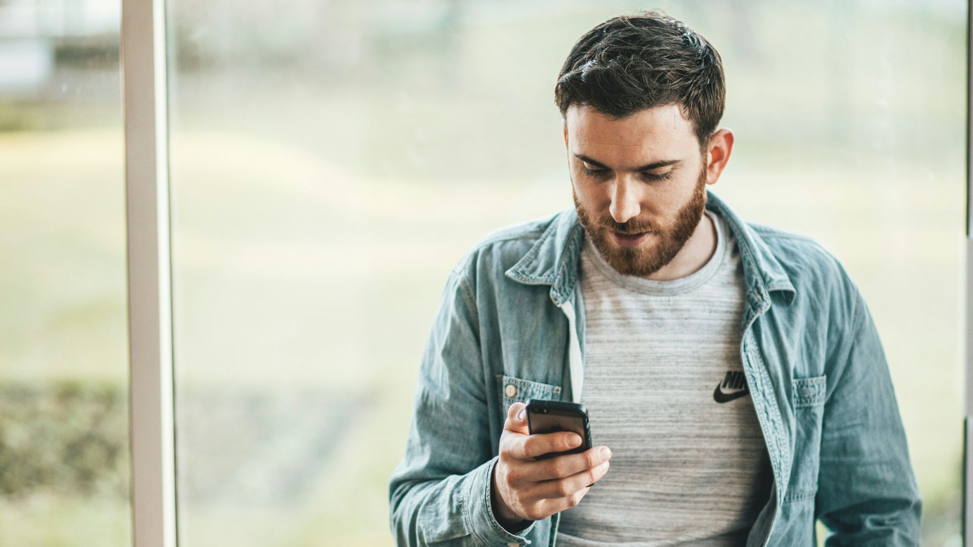 man holding a smartphone near the window