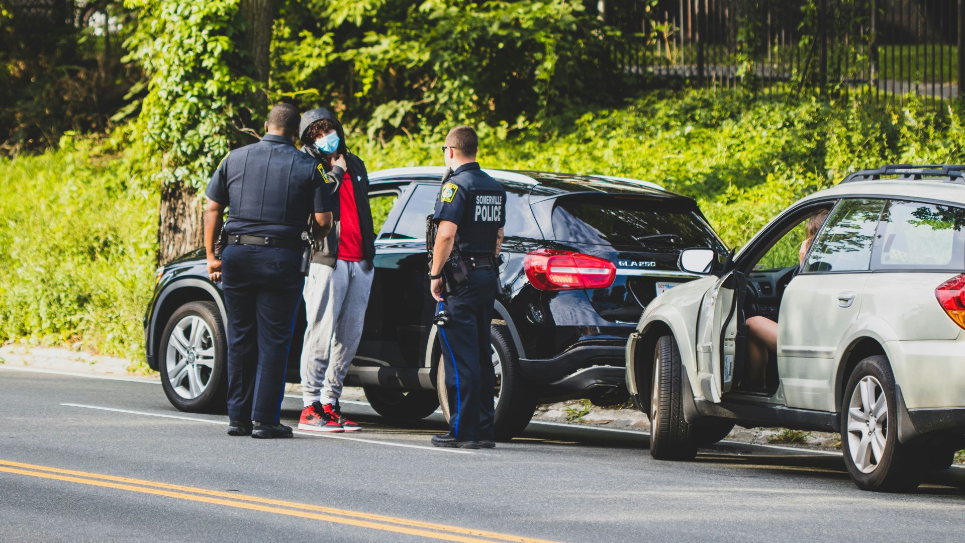 man in black t-shirt and black pants standing beside black suv during daytime