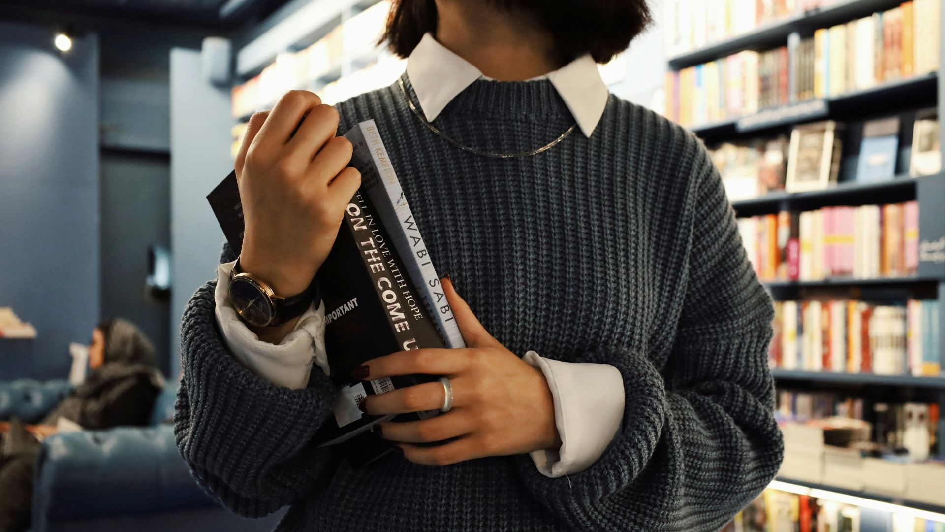 A woman standing in a library holding a book