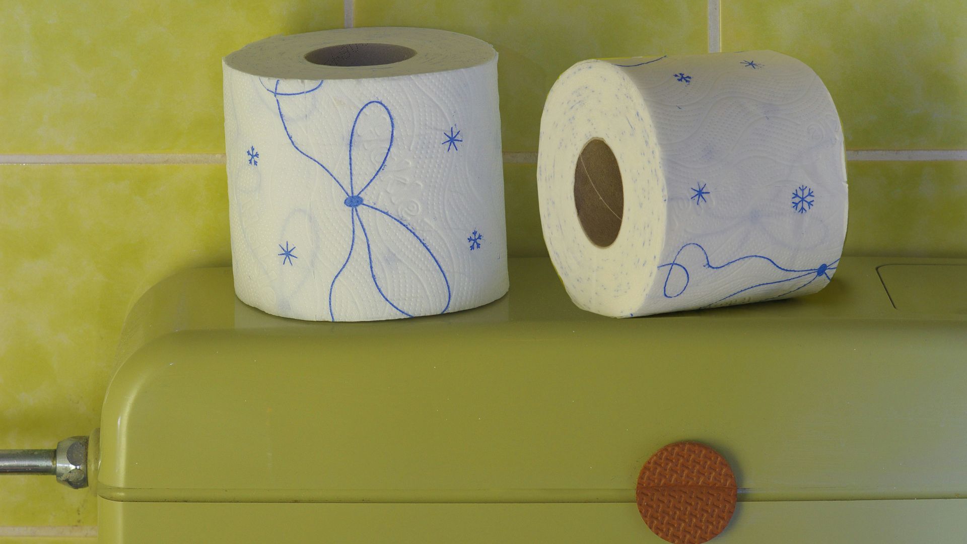 two rolls of toilet paper sitting on top of a green cabinet