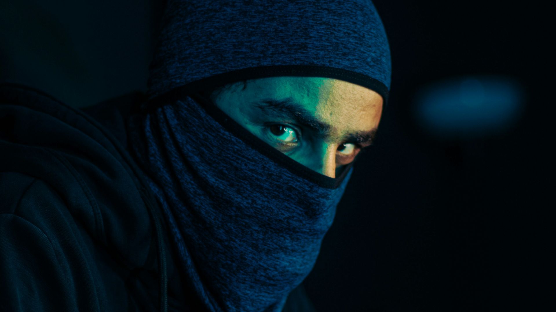 a man wearing a black hoodie and a blue mask