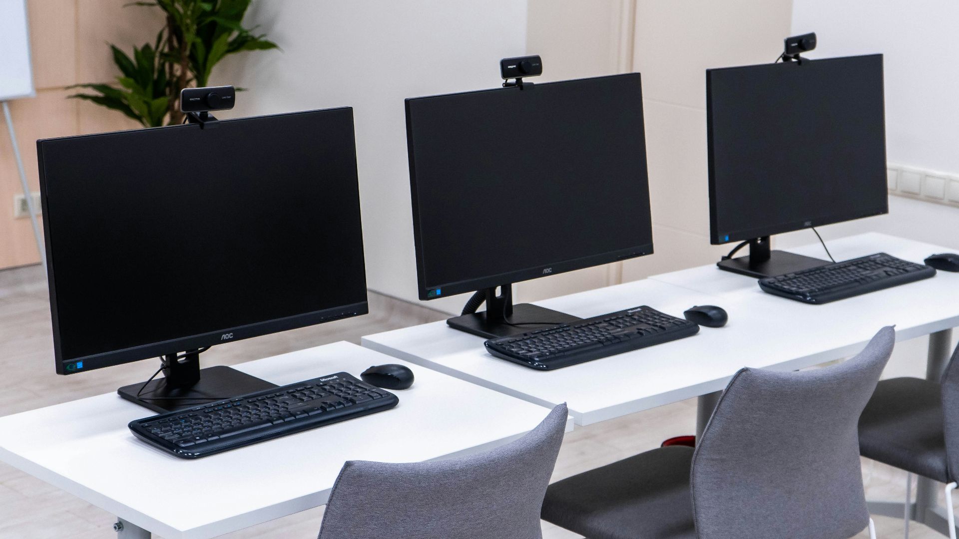 three computer monitors sitting on top of a white table