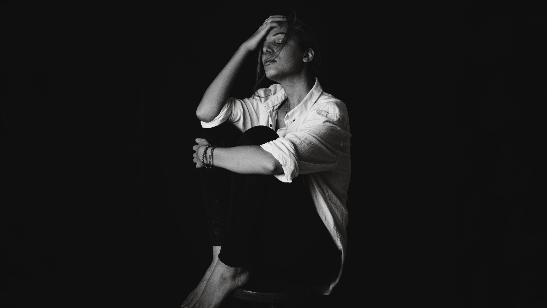 a black and white photo of a man sitting on a stool