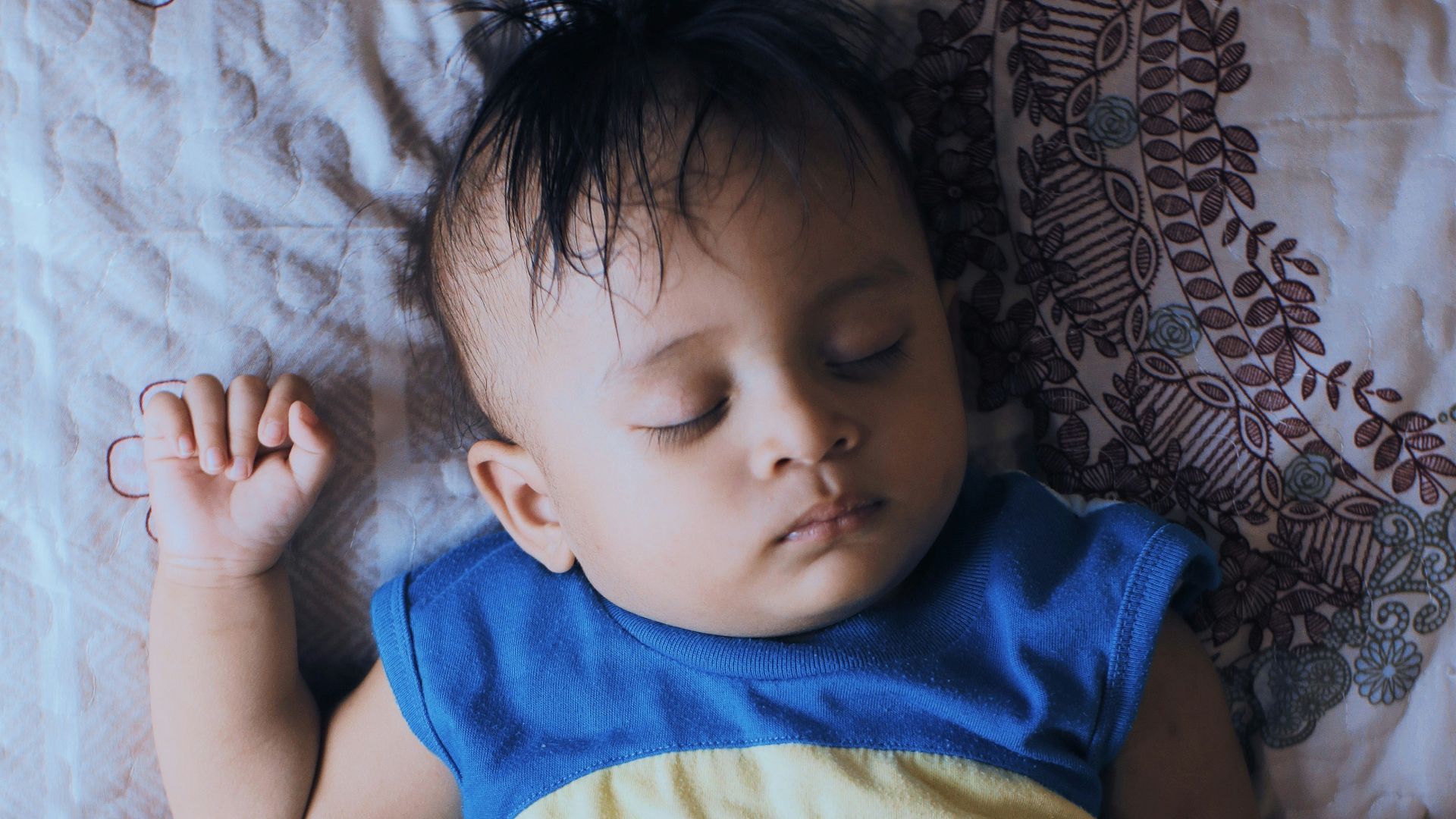 a baby laying on a bed with a teddy bear shirt on