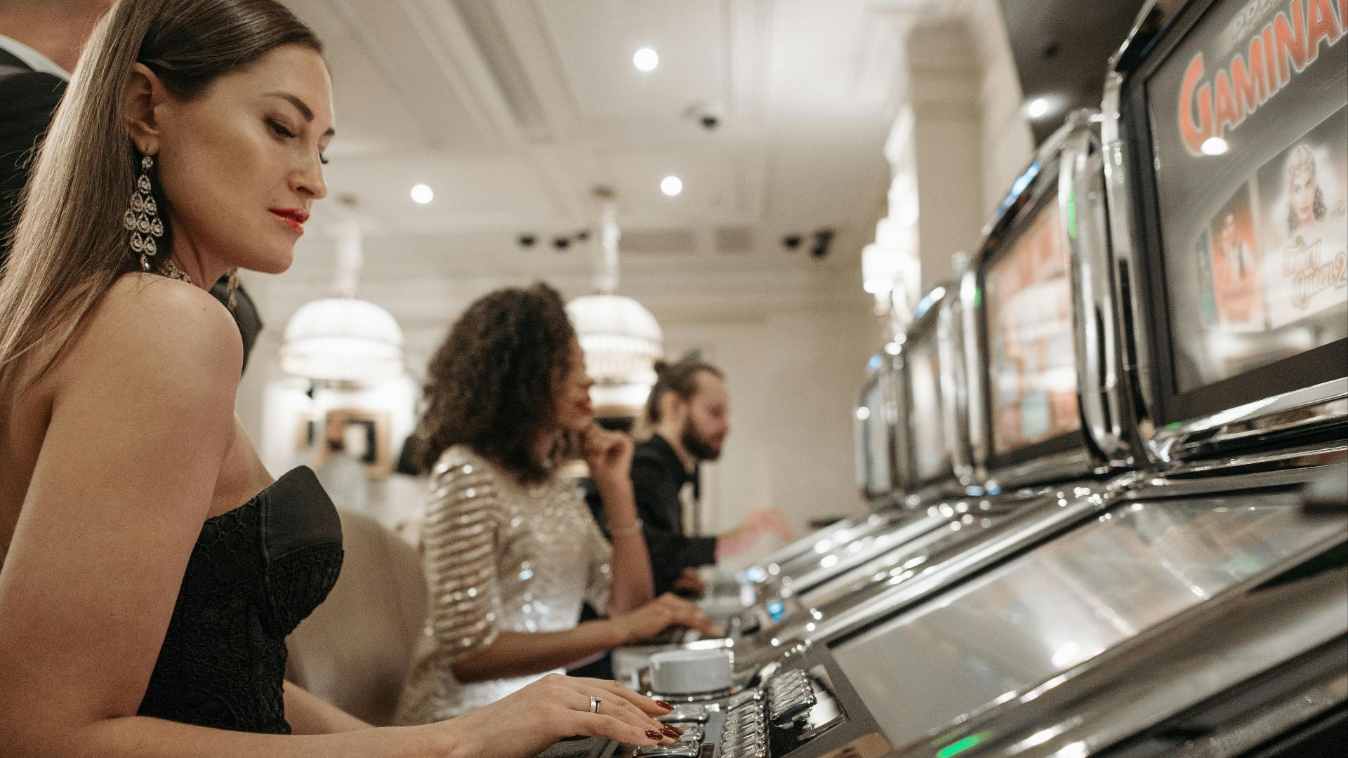 Stylish women engage in casino gaming at slot machines, showcasing elegance and excitement.